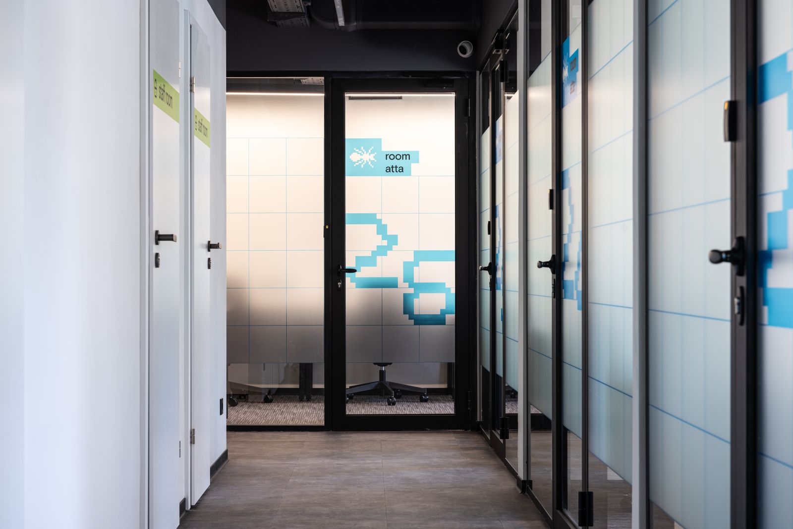 Hall with white and glass translucent walls and blue numbers on doors of various contemporary offices in modern business center